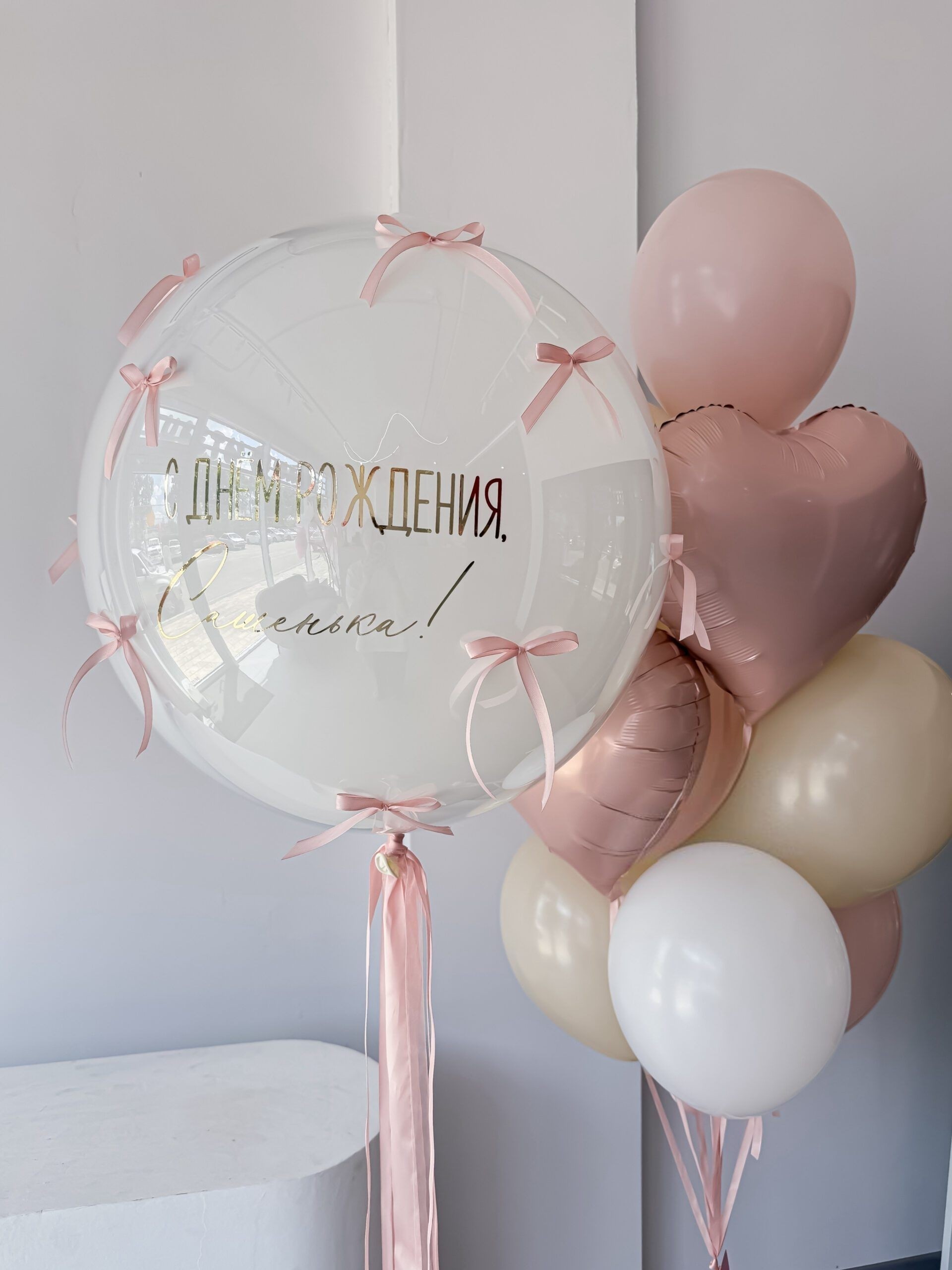 Композиция для девочки с большим прозрачным Bubble с поздравительной надписью, розовыми фольгированными сердцами, кремовыми, белыми и розовыми воздушными шарами